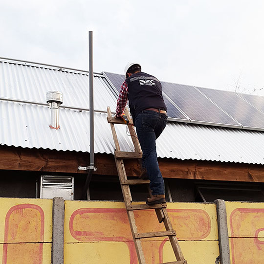Hombre subiendo por escaleras al techo con paneles solares